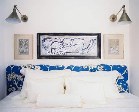 umetničke slike i zidne lampe u maloj spavaćoj sobi